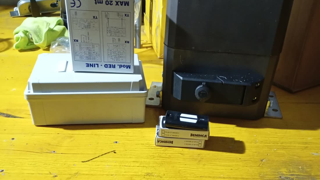 Banco di lavoro con un motore per cancello scorrevole, le fotocellule e la staffa di fissaggio, pronti per l'installazione